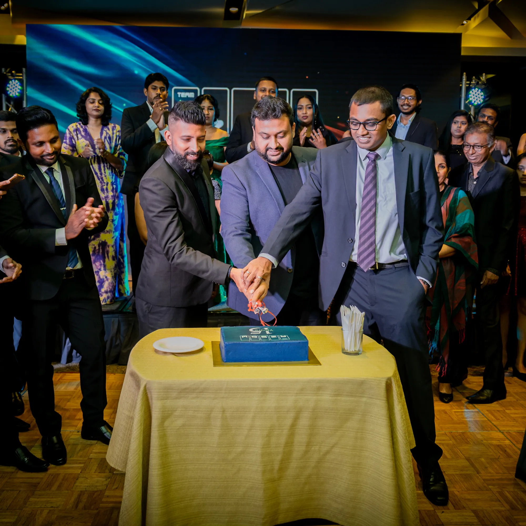 Azbow leadership cutting an anniversary cake with the team applauding around them